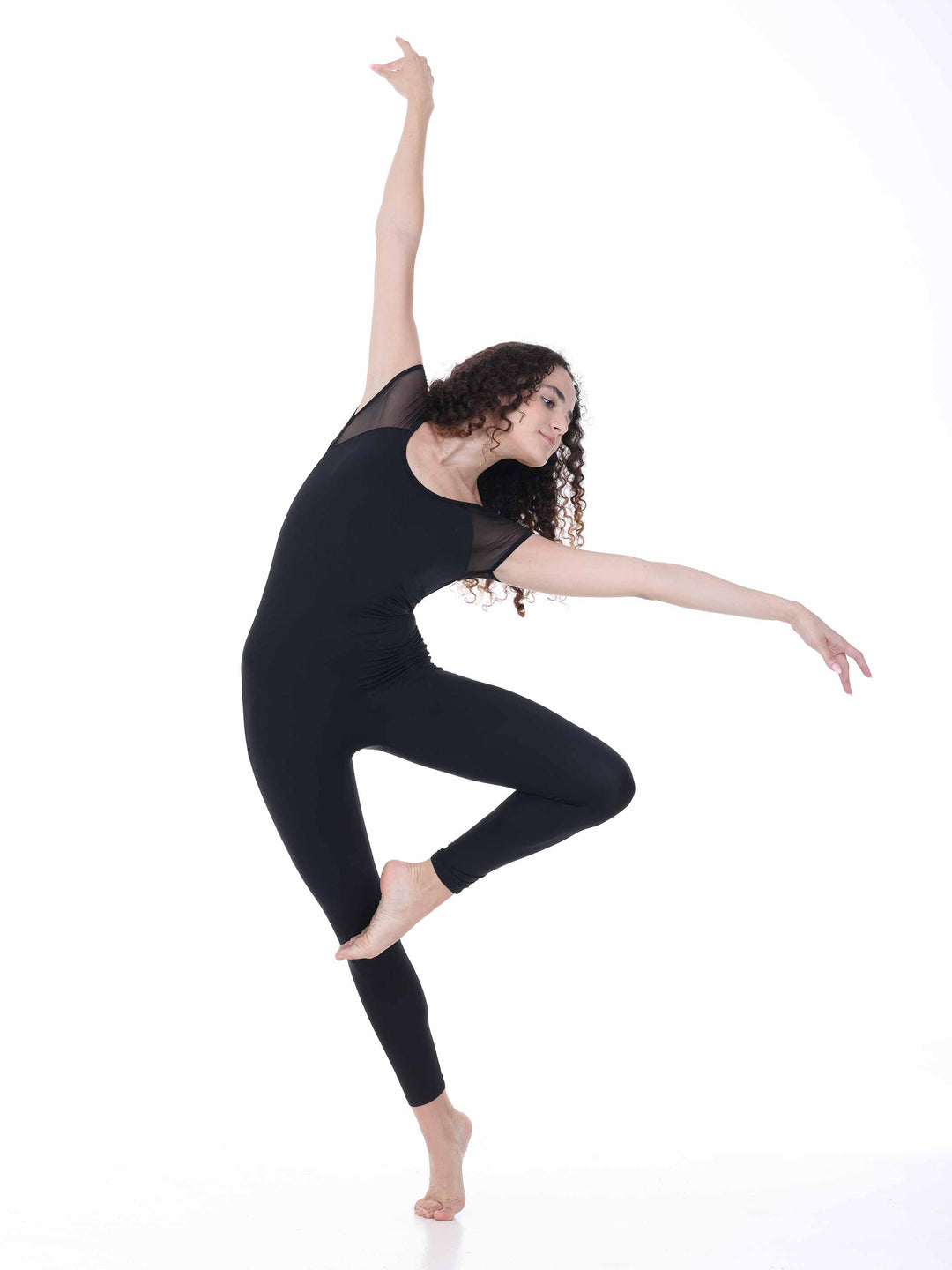 Danseuse portant la unitard de danse Sway – modèle Sheer Cap Sleeve Dance Unitard en negro, exécutant une pose de danza moderna avec un bras levé, sur fond blanco.