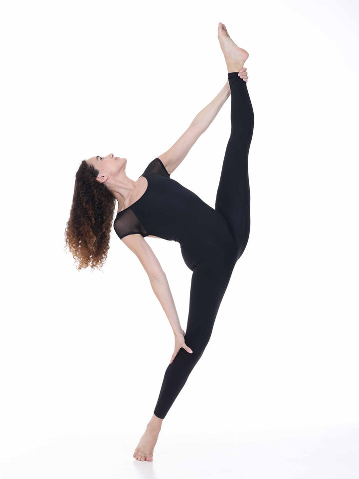 Danseuse portant la unitard de danse Sway – modèle Sheer Cap Sleeve Dance Unitard en negro, réalisant une extension de jambe haute en position de danza contemporánea, sur fond blanco.