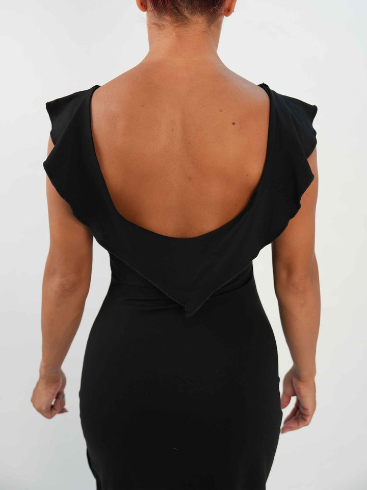 Femme portant une robe noire de danse latine sans manches, avec encolure volantée et ourlet asymétrique, associée à des collants résille et des chaussures de danse ornées. Tenue élégante et fluide, parfaite pour la salsa ou le ballroom. - vue de l&