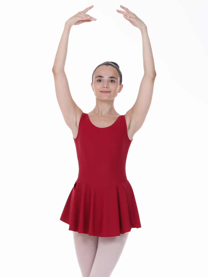 Danseuse in position of ballet with a dress of danse bordeaux – bretelles larges and skirt évasée.